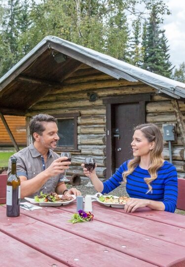 Couple eating al fresco amidst Alaska cabins