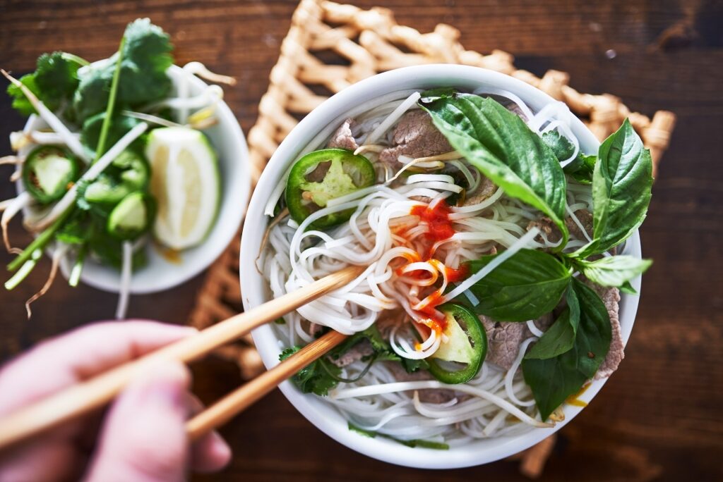 Person eating a bowl of Pho